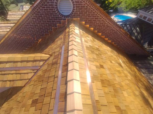 Cedar shake ridge with copper step flashing at a brick gable